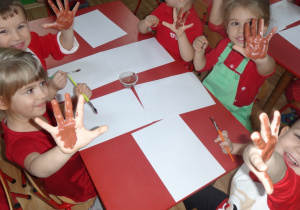 Dzieci pomalowały dłonie farbą, by odbić je na kartce papieru
